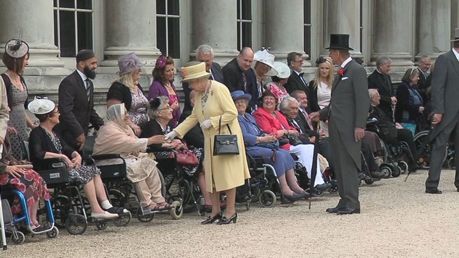 Queen Elizabeth II greeting guests in wheelchairs on the lawn at a Buckingham Palace garden party